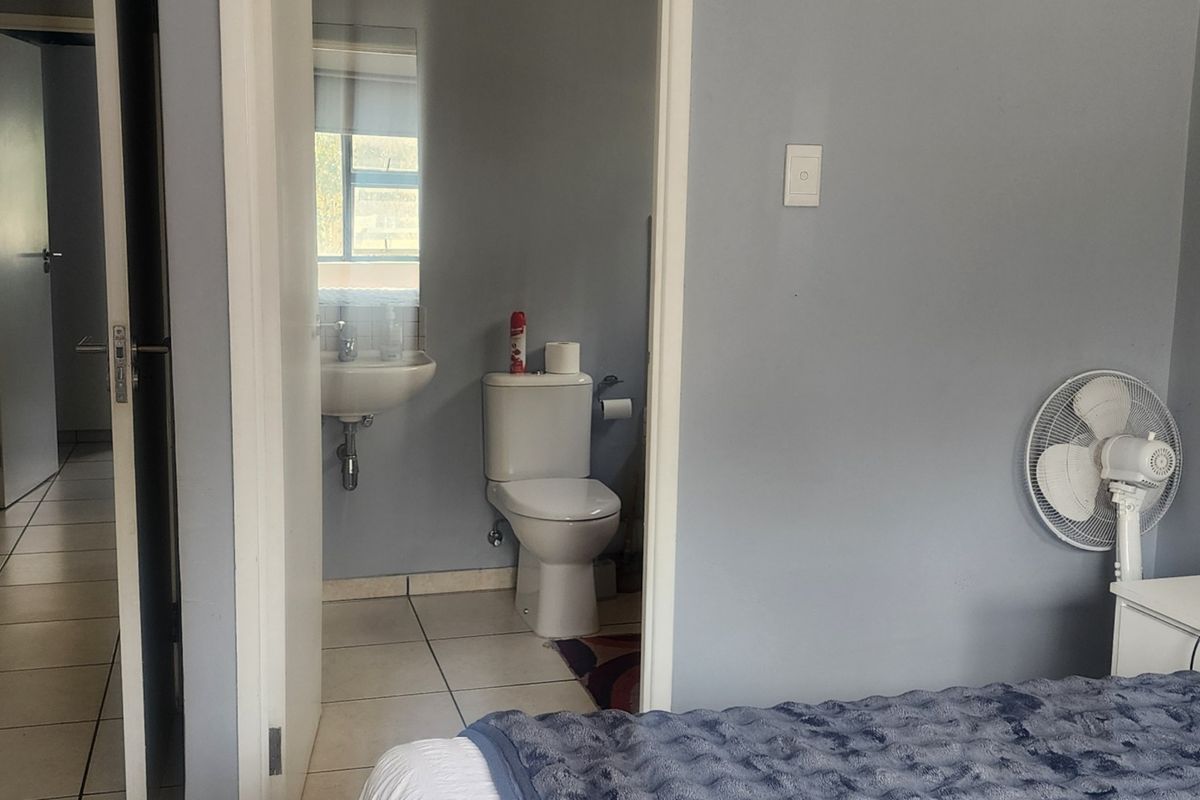 A compact en-suite bathroom featuring a wall-mounted basin and standard toilet, accessible directly from the bedroom area.