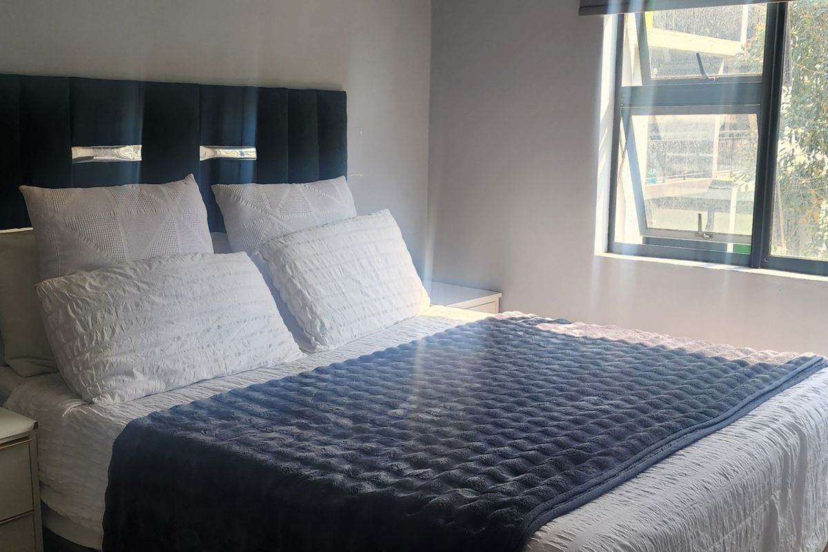 A well-lit bedroom featuring a modern window with aluminium frames, providing natural light and a view of the exterior.
