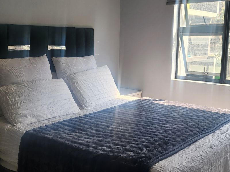 A well-lit bedroom featuring a modern window with aluminium frames, providing natural light and a view of the exterior.
