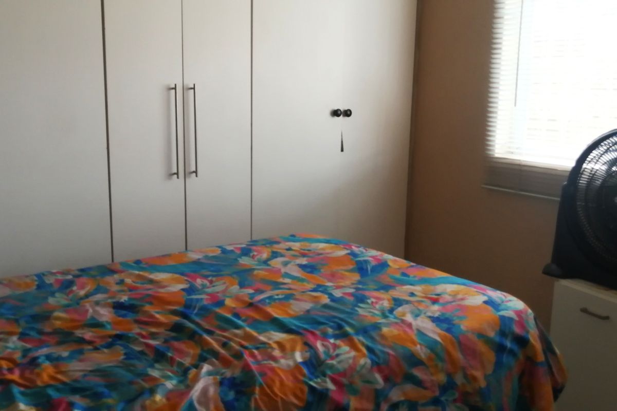 A bedroom featuring built-in cupboards and venetian blinds, providing functional storage and adjustable natural light.
