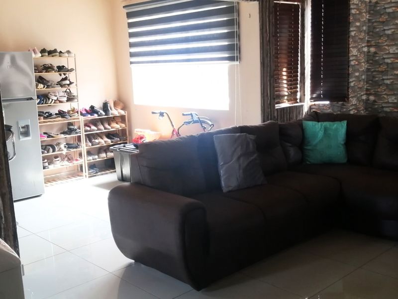 A living room featuring tiled flooring, venetian blinds, and a stone-cladding feature wall, offering a functional space for relaxation.