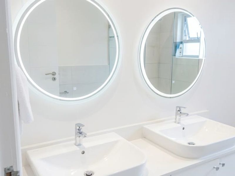 Modern bathroom featuring a double vanity with integrated LED mirrors, contemporary basin sinks, and chrome fixtures.