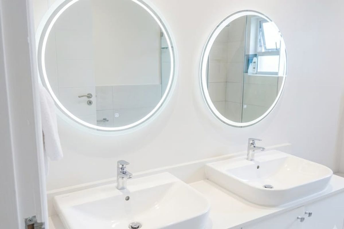 Modern bathroom featuring a double vanity with integrated LED mirrors, contemporary basin sinks, and chrome fixtures.