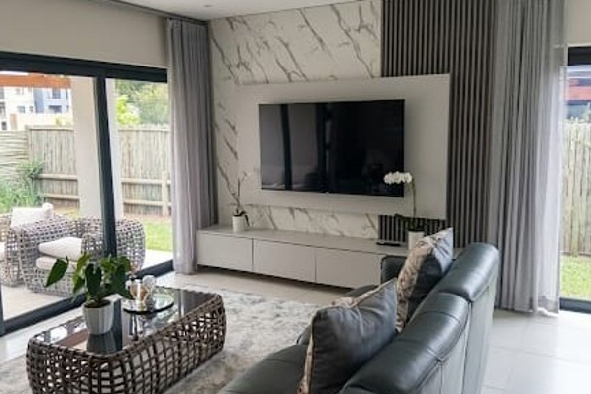 Modern living room featuring a marble-look feature wall, built-in media cabinetry, slatted timber accents, and large sliding doors opening to the garden.