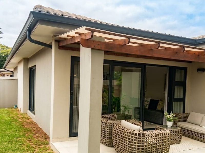 A covered patio area featuring a timber pergola, tiled flooring, and sliding glass doors providing seamless access to the interior living space.
