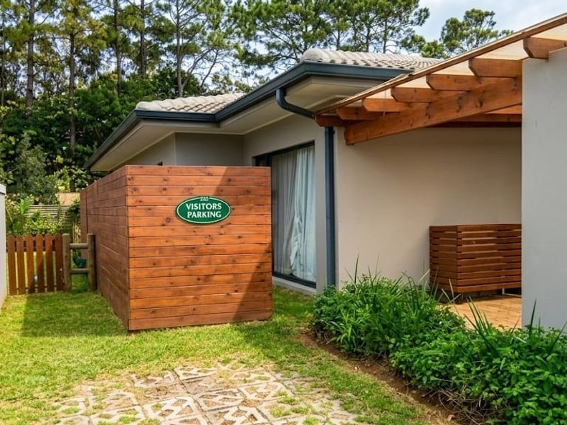 Front exterior view of the townhouse featuring a timber pergola, privacy screen, and paved walkway leading to the entrance.