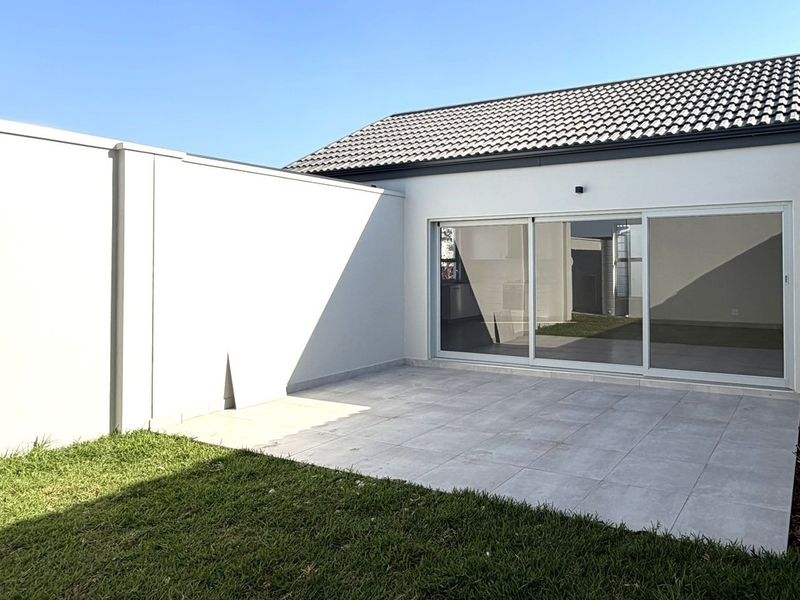 A clean, modern paved patio area featuring large sliding glass doors that provide seamless access to the interior living space.