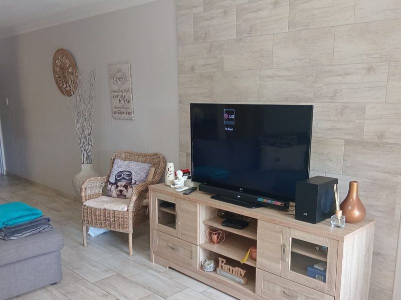 Living room featuring a modern wood-look tiled feature wall and neutral ceramic floor tiles throughout the space.