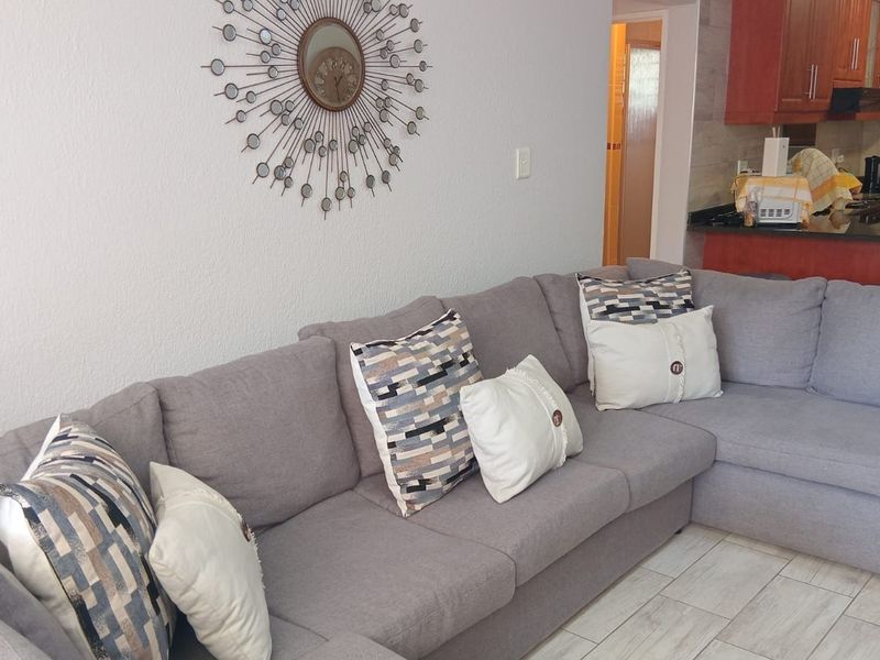 Open plan living area featuring tiled flooring and a kitchen with dark wood cabinetry and granite countertops.