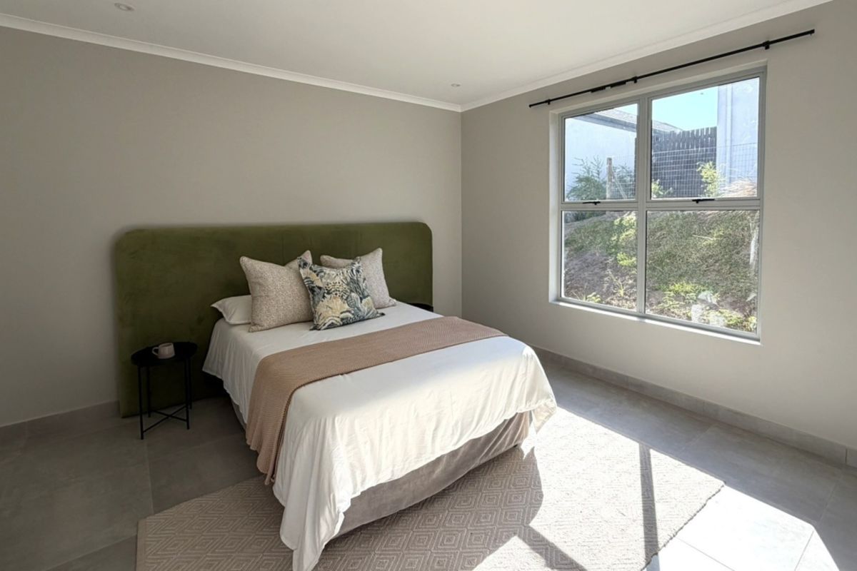 A bright and neutral bedroom featuring large windows, tiled flooring, and recessed ceiling lighting, offering a clean and modern living space.