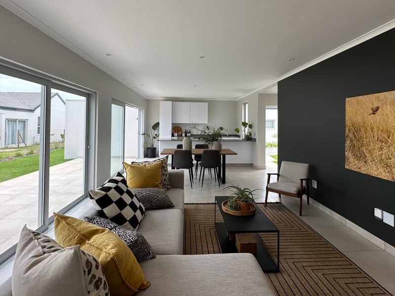 Modern open-plan living and kitchen area featuring tiled floors, recessed lighting, and large sliding glass doors providing seamless access to the outdoor patio.