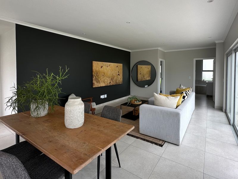 Spacious open-plan living and dining area featuring large sliding glass doors, modern tiled flooring, and a striking black accent wall.