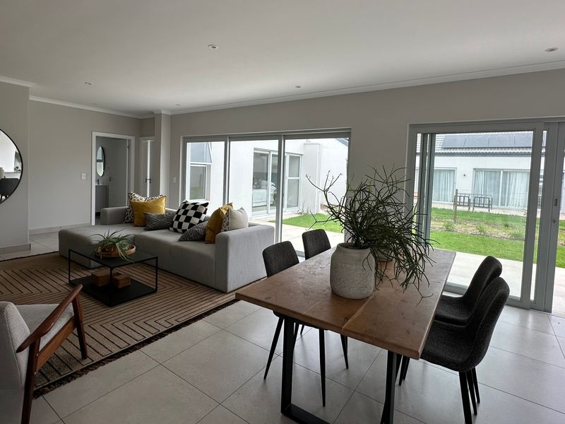 Spacious open-plan living and dining area featuring large sliding glass doors that provide seamless access to the outdoor garden space.