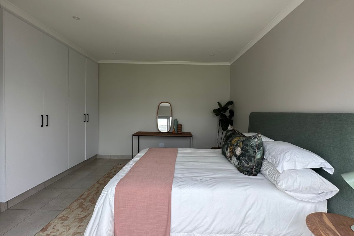 A well-maintained bedroom featuring neutral walls, tiled flooring, recessed downlighting, and extensive built-in cupboard storage.