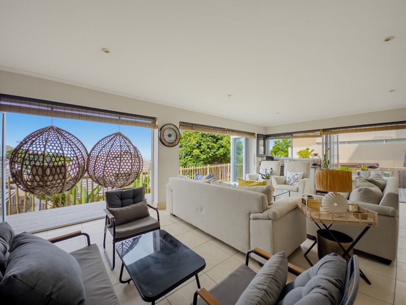 Spacious open-plan living area featuring large stacking glass doors that provide seamless access to the outdoor patio and abundant natural light.