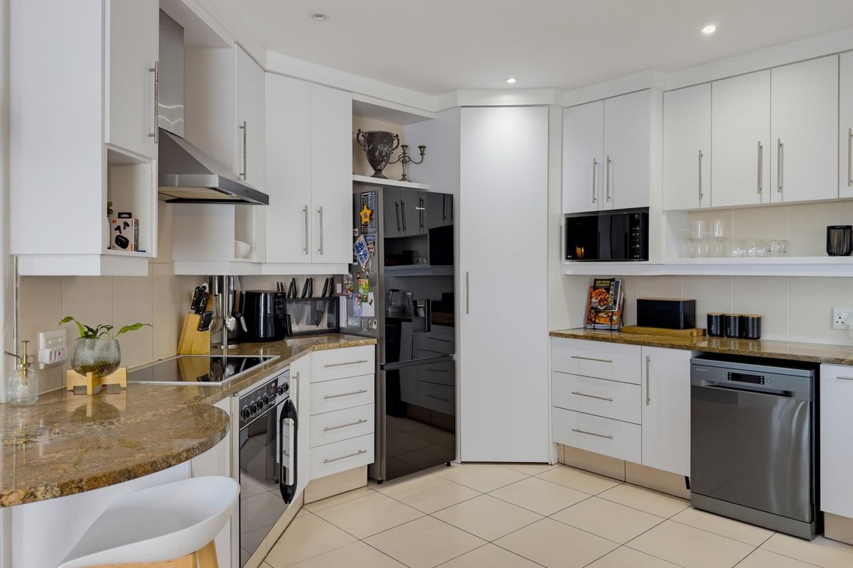 Modern kitchen featuring white cabinetry, granite countertops, integrated appliances, and tiled flooring with recessed lighting.