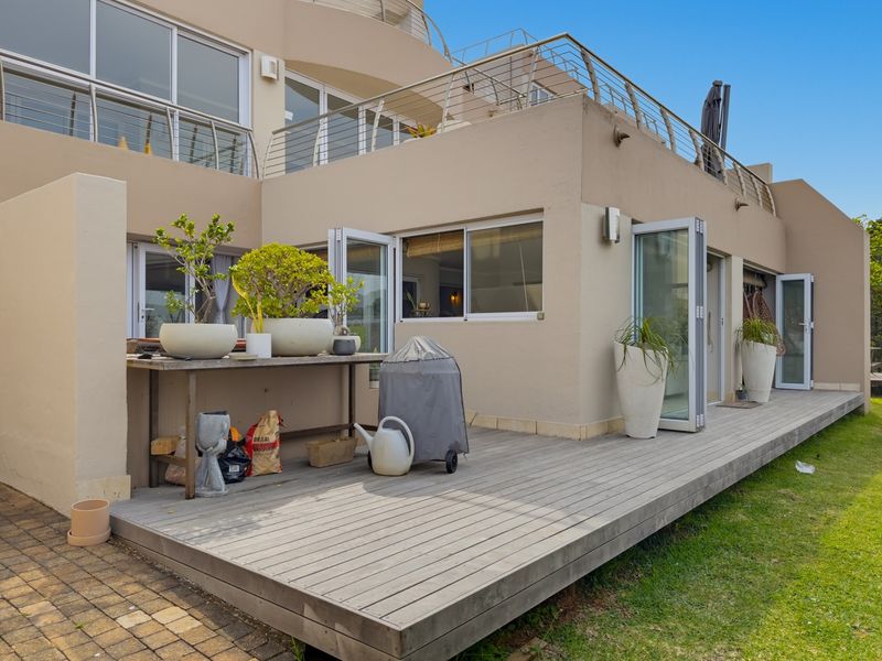 Spacious ground floor timber deck featuring bi-fold doors providing seamless indoor-outdoor flow, complemented by stainless steel balustrades and exterior wall lighting.