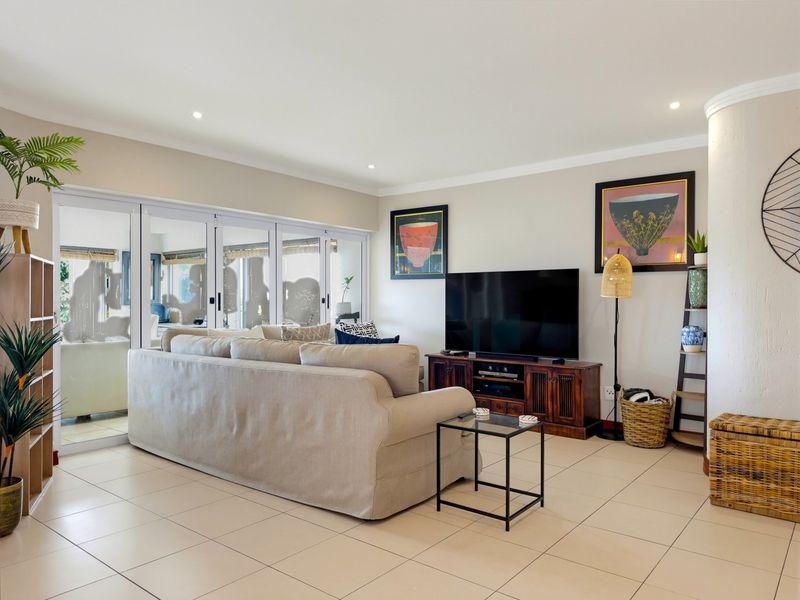 Spacious living room featuring neutral tiled flooring, recessed lighting, and large sliding glass doors that provide access to the patio area.