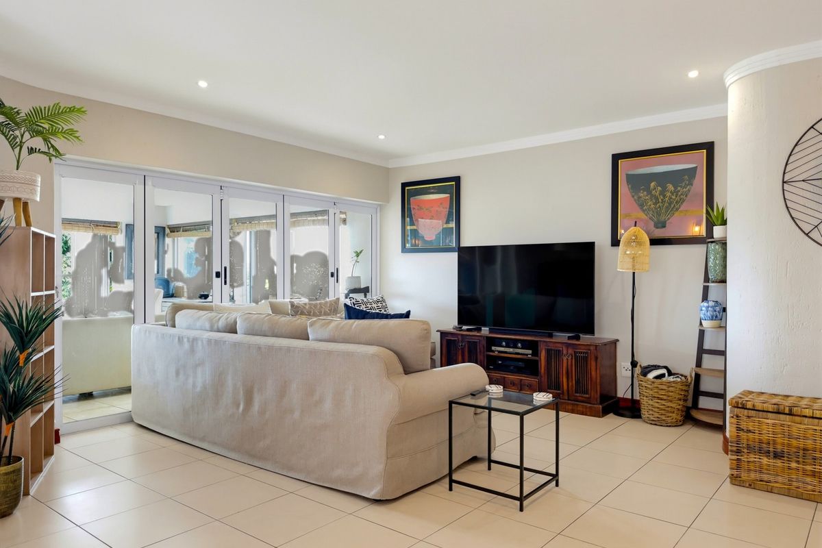 Spacious living room featuring neutral tiled flooring, recessed lighting, and large sliding glass doors that provide access to the patio area.