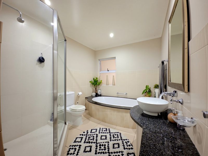 A well-maintained bathroom featuring a glass shower enclosure, a built-in bathtub, and a granite vanity with a modern vessel sink.