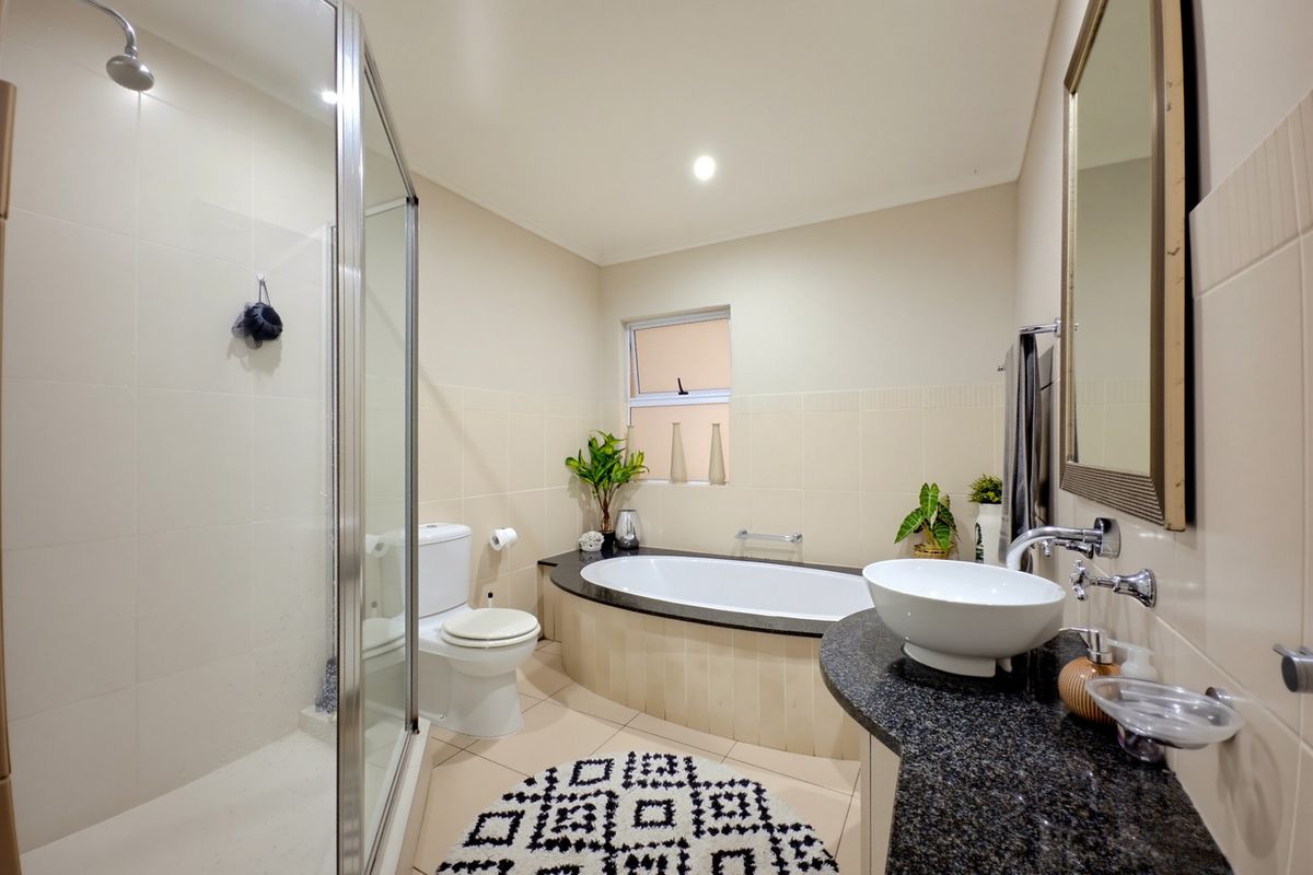 A well-maintained bathroom featuring a glass shower enclosure, a built-in bathtub, and a granite vanity with a modern vessel sink.