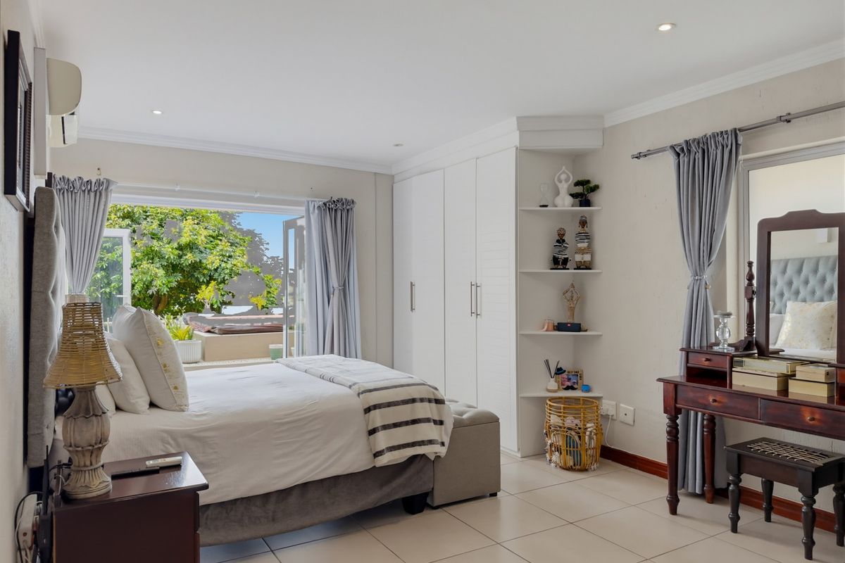 Spacious bedroom featuring built-in cupboards, tiled flooring, recessed lighting, and direct access to an outdoor patio area through sliding doors.