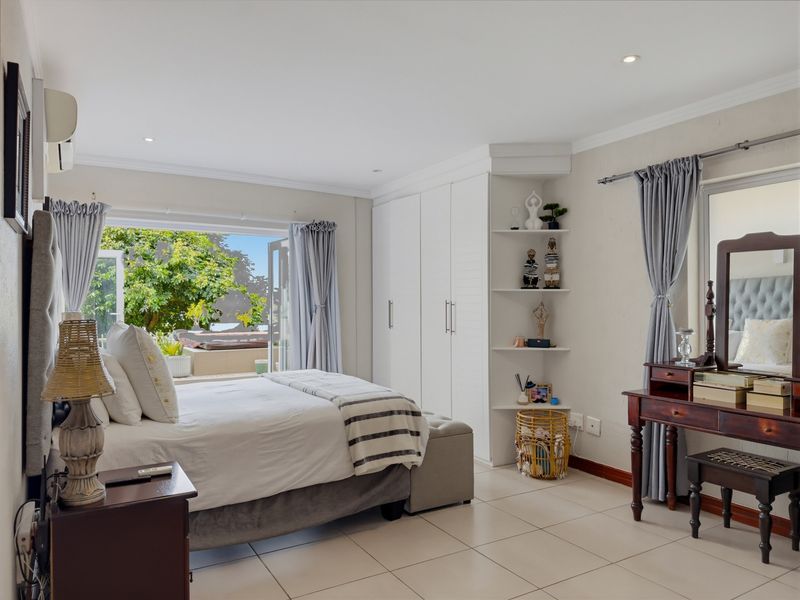 Spacious bedroom featuring built-in cupboards, tiled flooring, recessed lighting, and direct access to an outdoor patio area through sliding doors.