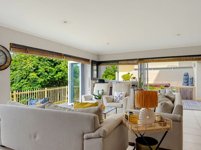 Spacious open-plan living area featuring large bi-fold doors that open onto an expansive outdoor timber deck, creating a seamless indoor-outdoor flow.