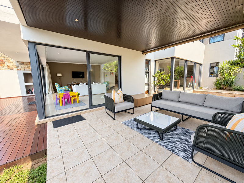 Spacious covered patio featuring tiled flooring, recessed lighting, and seamless access to the interior living area through large sliding glass doors.