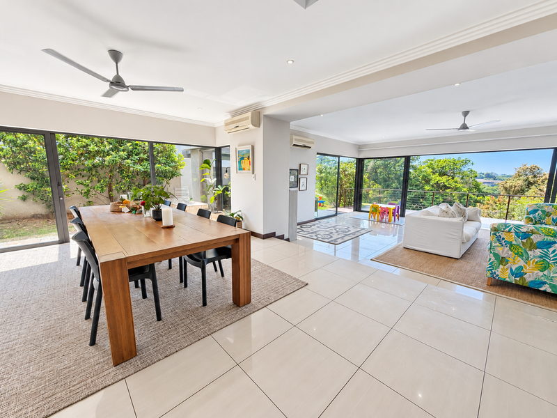 Spacious open-plan living and dining area featuring large sliding glass doors, tiled flooring, and dual split-system air conditioning units.
