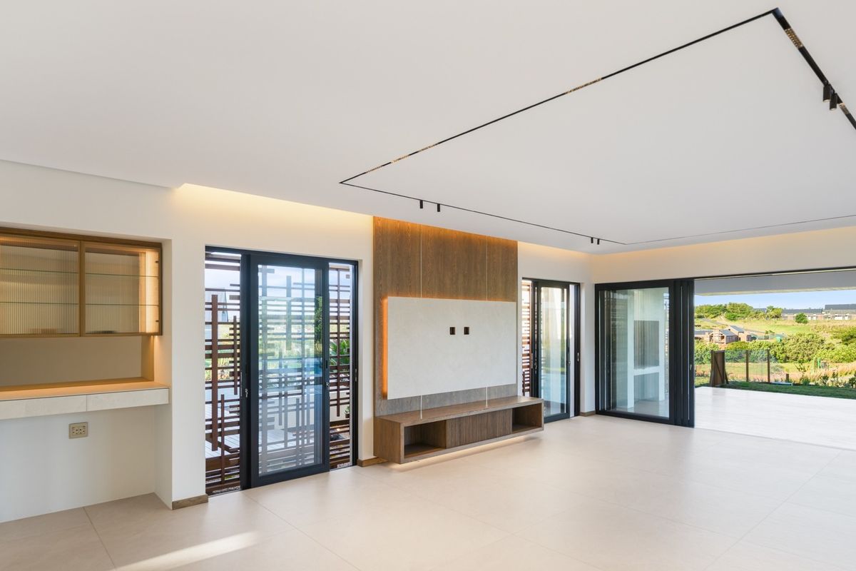 Modern, spacious living area featuring high-end finishes, built-in cabinetry, recessed lighting, and large sliding doors opening to an outdoor patio with scenic views.