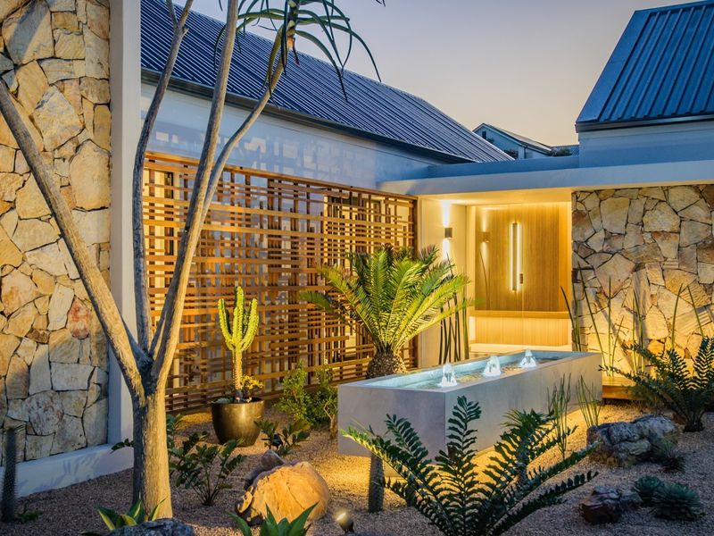 A beautifully landscaped rear courtyard featuring stone-clad walls, a modern water feature, and architectural timber screening with integrated ambient lighting.