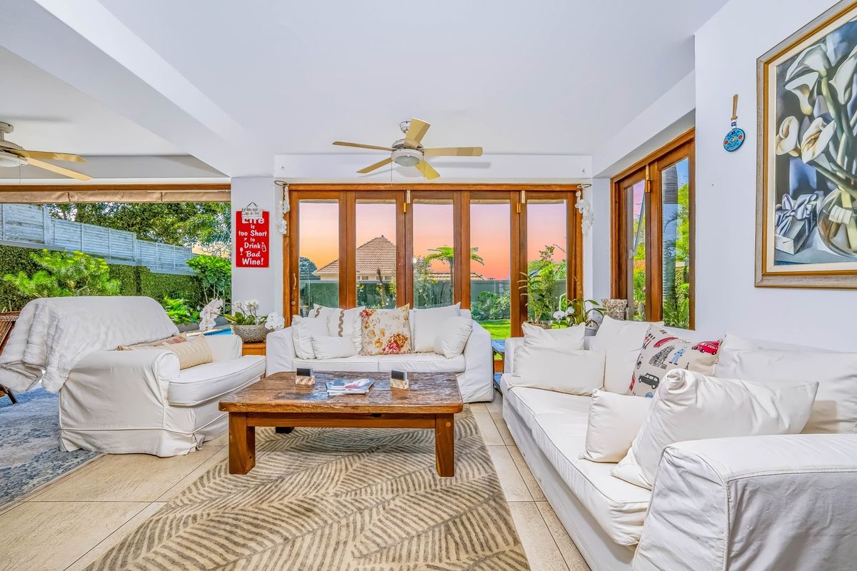Spacious living room featuring tiled flooring, ceiling fans, and large timber-framed folding doors that open to the garden area.