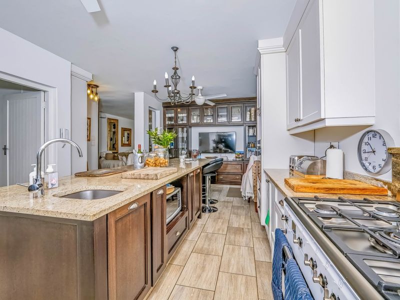 A well-appointed kitchen featuring granite countertops, a gas hob, and extensive built-in cabinetry with a central island and integrated sink.