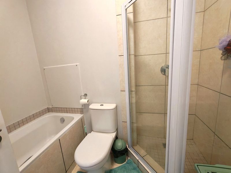 A functional bathroom featuring a built-in bathtub, a separate shower enclosure with tiled walls, and a standard toilet.
