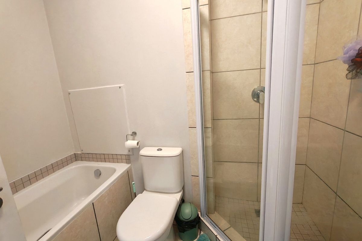 A functional bathroom featuring a built-in bathtub, a separate shower enclosure with tiled walls, and a standard toilet.