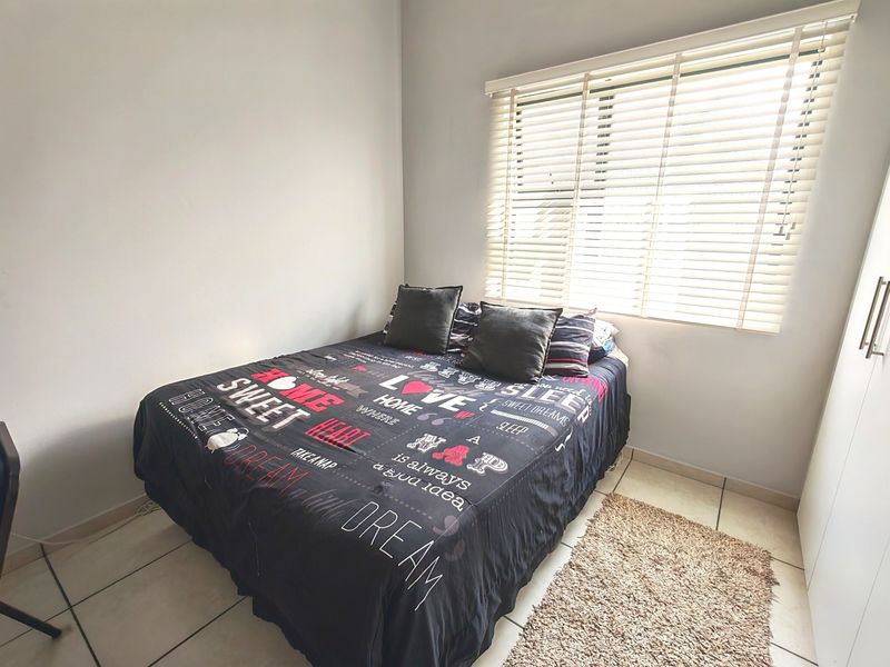A functional bedroom featuring tiled flooring, a built-in wardrobe, and venetian blinds allowing natural light.