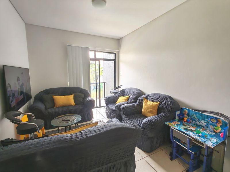 A living room area featuring tiled flooring and a sliding glass door providing access to an outdoor space.