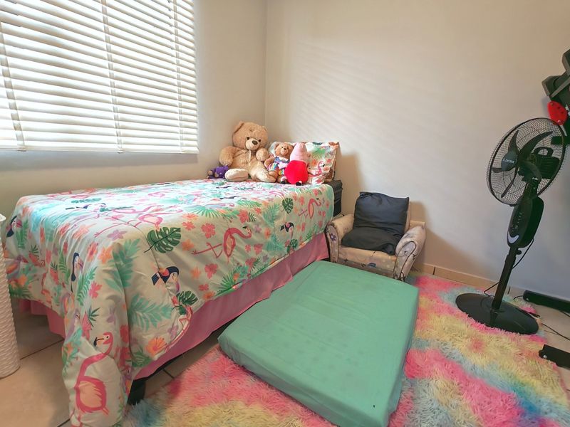 A functional bedroom featuring tiled flooring and venetian blinds, providing a neutral base for personalization.