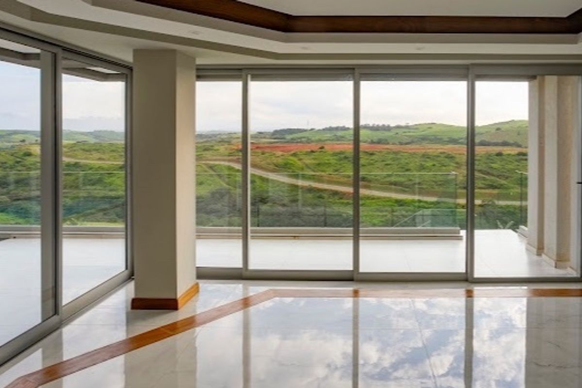 Spacious, empty living area featuring polished marble floors, recessed ceiling details, and expansive sliding glass doors opening to a scenic outdoor view.