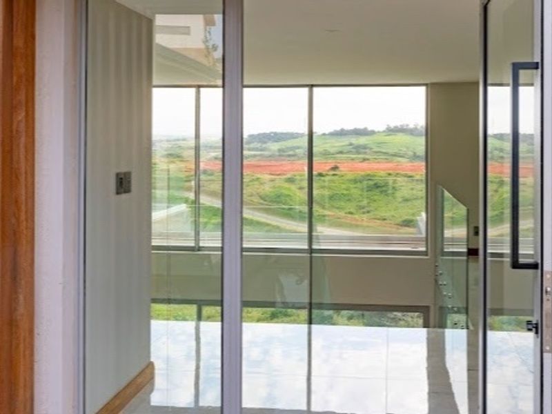 Modern entrance featuring a sleek glass pivot door, timber wall accents, and polished tile flooring with expansive views of the surrounding landscape.