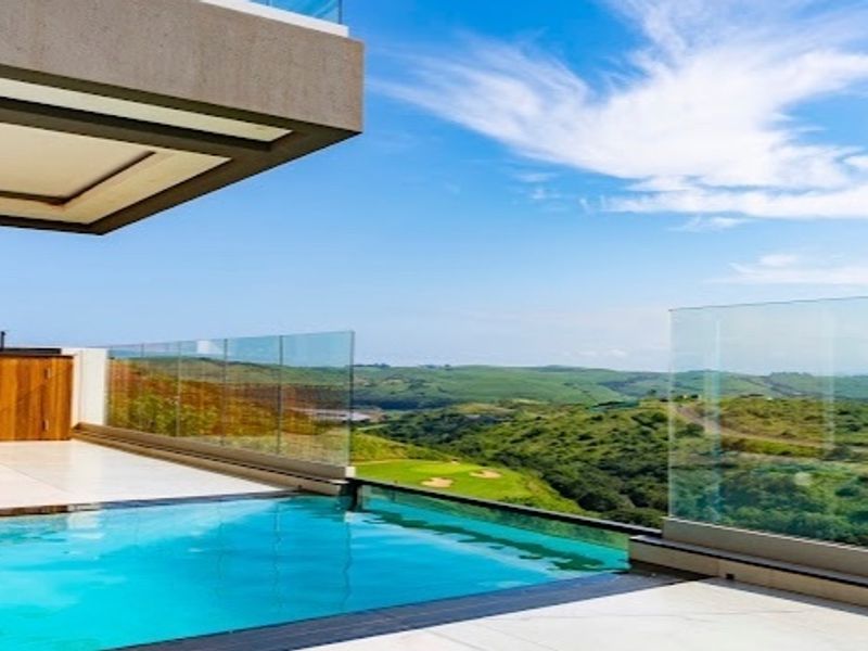 Modern infinity edge swimming pool with glass balustrades and expansive views over the surrounding landscape.