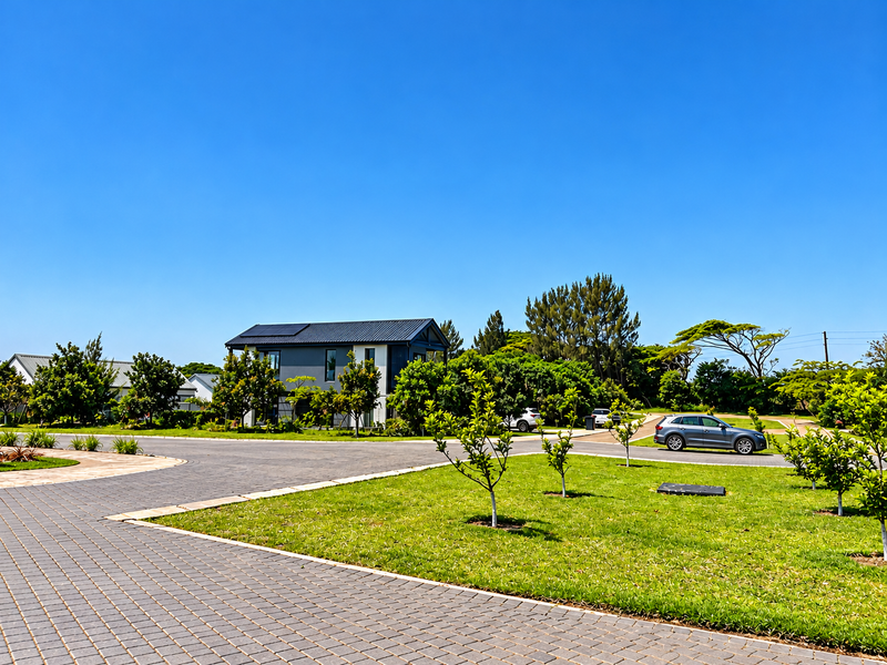 A well-maintained residential street view featuring paved driveways, manicured lawns, and a modern two-story home with solar panels.