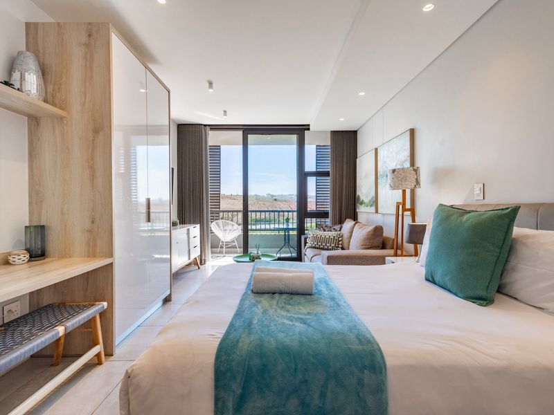 Modern bedroom featuring built-in cabinetry, recessed lighting, and direct access to a private balcony with scenic views.
