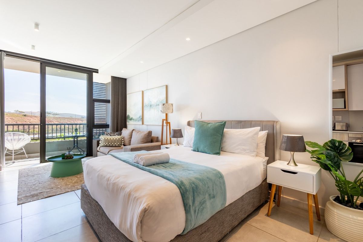 Modern bedroom featuring tiled floors, recessed lighting, and a large sliding glass door providing access to a private balcony with scenic views.