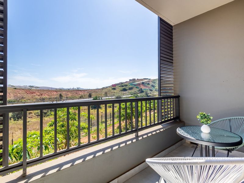 A modern covered balcony featuring a metal balustrade and slatted privacy screen, offering expansive views of the surrounding landscape.
