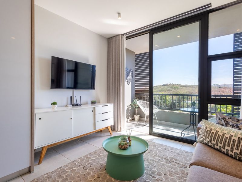 Modern living room featuring large sliding glass doors that open onto a private balcony with scenic views and abundant natural light.
