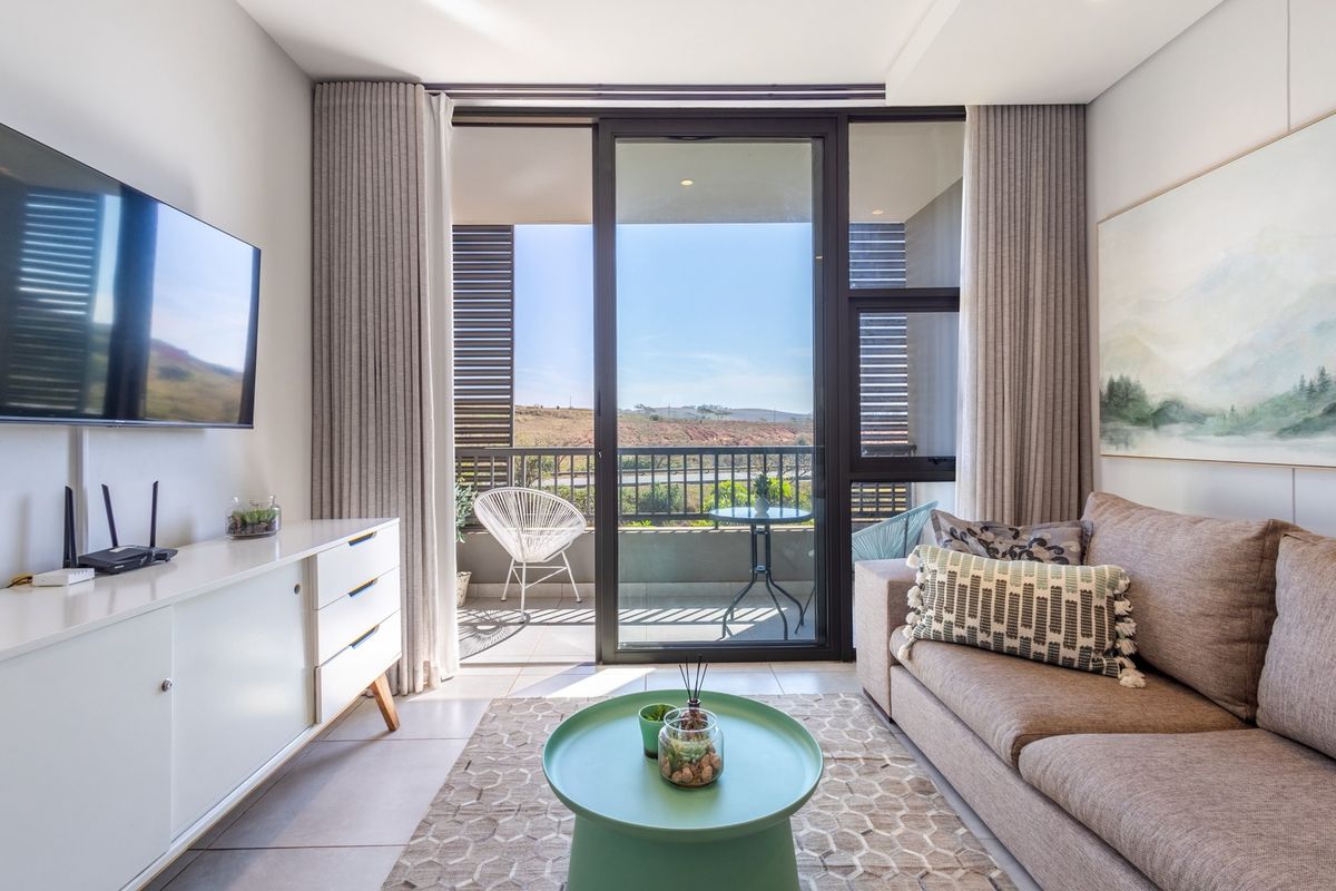 A bright and modern living room featuring large sliding glass doors that open onto a private balcony with scenic views.