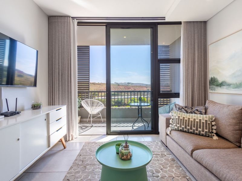 A bright and modern living room featuring large sliding glass doors that open onto a private balcony with scenic views.