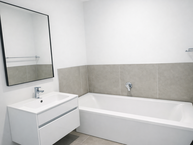 Modern bathroom featuring a sleek white vanity with basin, a clean bathtub with wall-mounted mixer, and neutral tiled splashbacks.